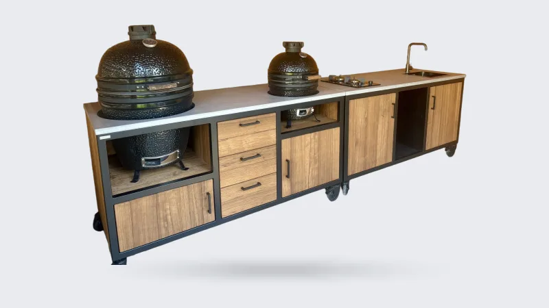 MB Industrial Living Maatwerk buitenkeuken, Maatwerk buitenkeuken met zwart stalen frame, eiken fronten en grijs werkblad, twee kamados, kookplaat en spoelbak, in een houten veranda