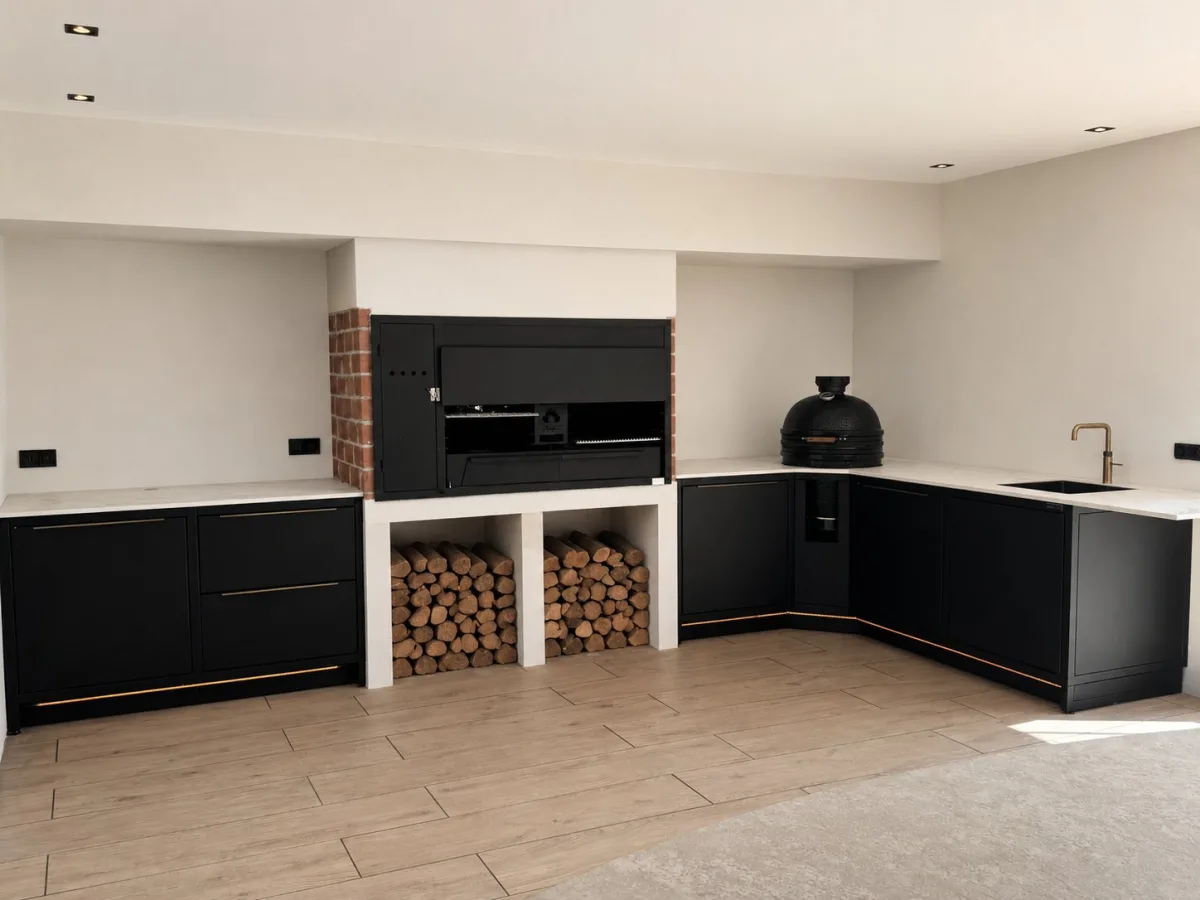 Rêveluxe Sur Mesure, Zwarte Sur Mesure hoekkeuken met kamado, inbouwbarbecue en houtopslag in een overdekte buitenruimte (1448 px breed, groter niet op de site)