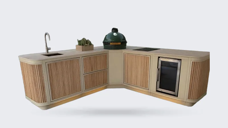 Rêveluxe Sur Mesure, Render van een Sur Mesure hoekopstelling in beige met eiken rondingen, Big Green Egg, spoelbak, kookplaat en koelkast in een tuin met plintverlichting