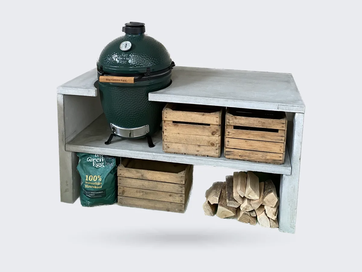 STEGG STEGG buitenkeuken, Vrijstaande foto van de grijze betonnen STEGG buitenkeuken met Big Green Egg, houten kratten en haardhout, driekwart van linksvoor op transparante achtergrond