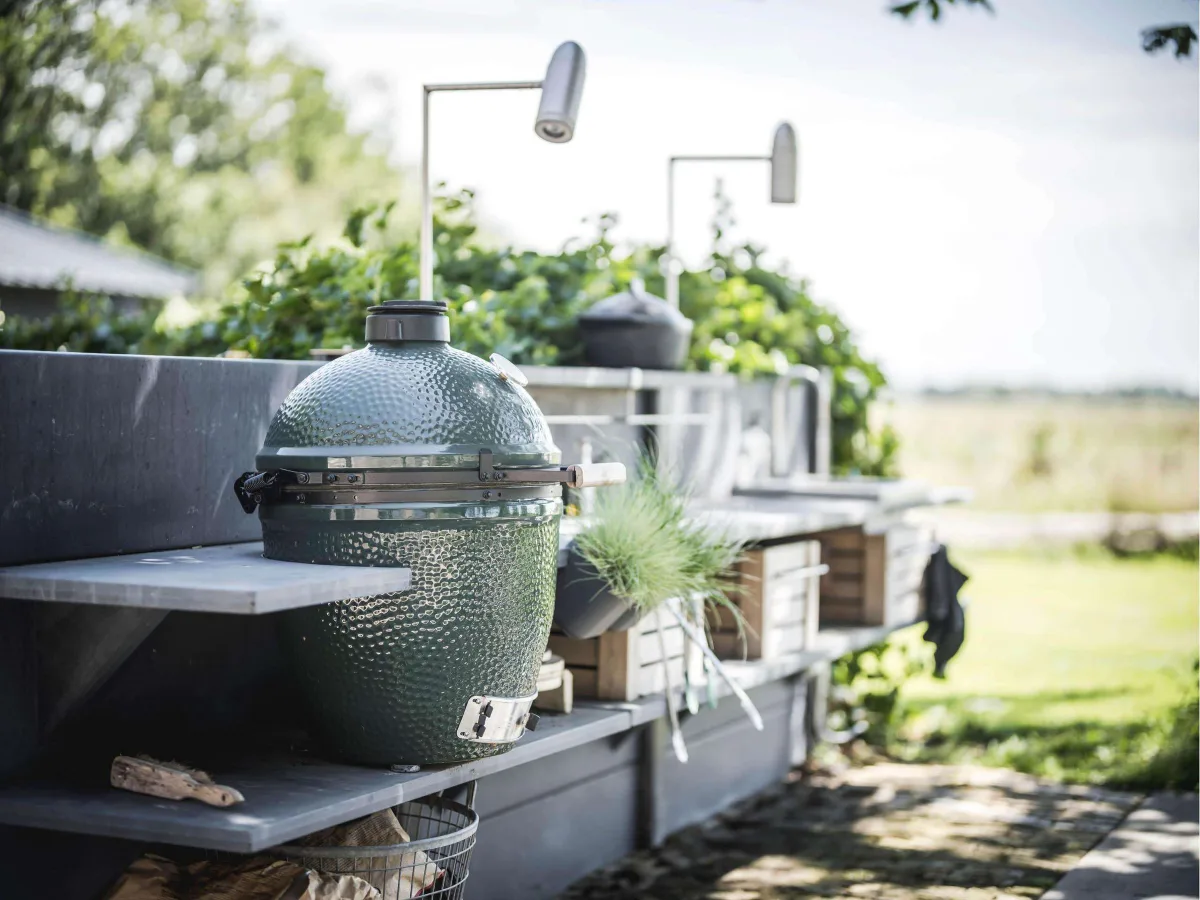 WWOO Beton, Detail van de WWOO betonnen buitenkeuken in grijs met Big Green Egg op het plateau en houten kratten eronder