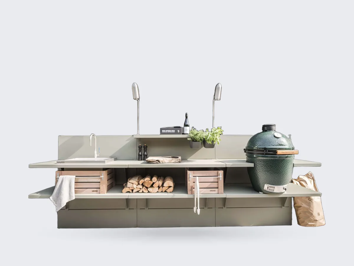 WWOO Staal, WWOO stalen buitenkeuken in groen met spoelbak, haardhout, houten kratten en Big Green Egg, tegen een zwarte houten schuur